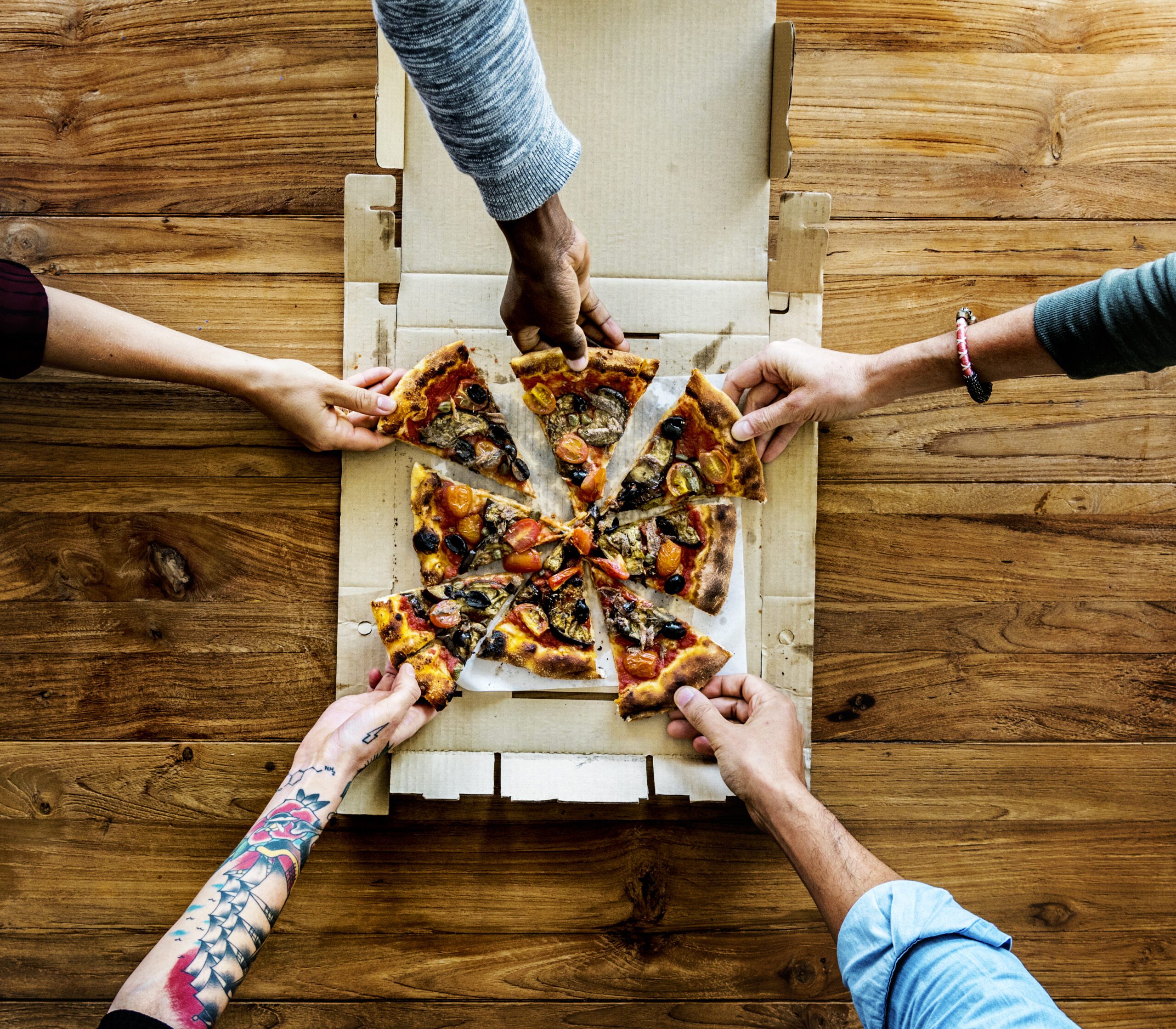 People Hands Grabbing Pizza From A Pizza Box