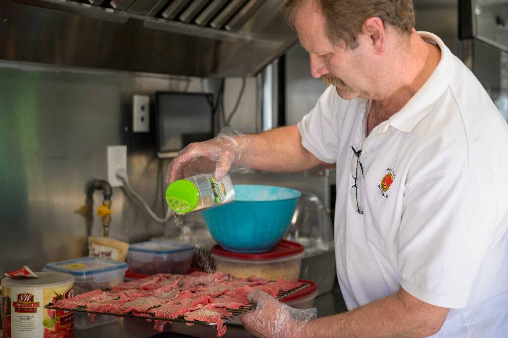 jeffrey johnson, owner of Leo's Smokin' Pizza, seasoning up some meat for the smoker.